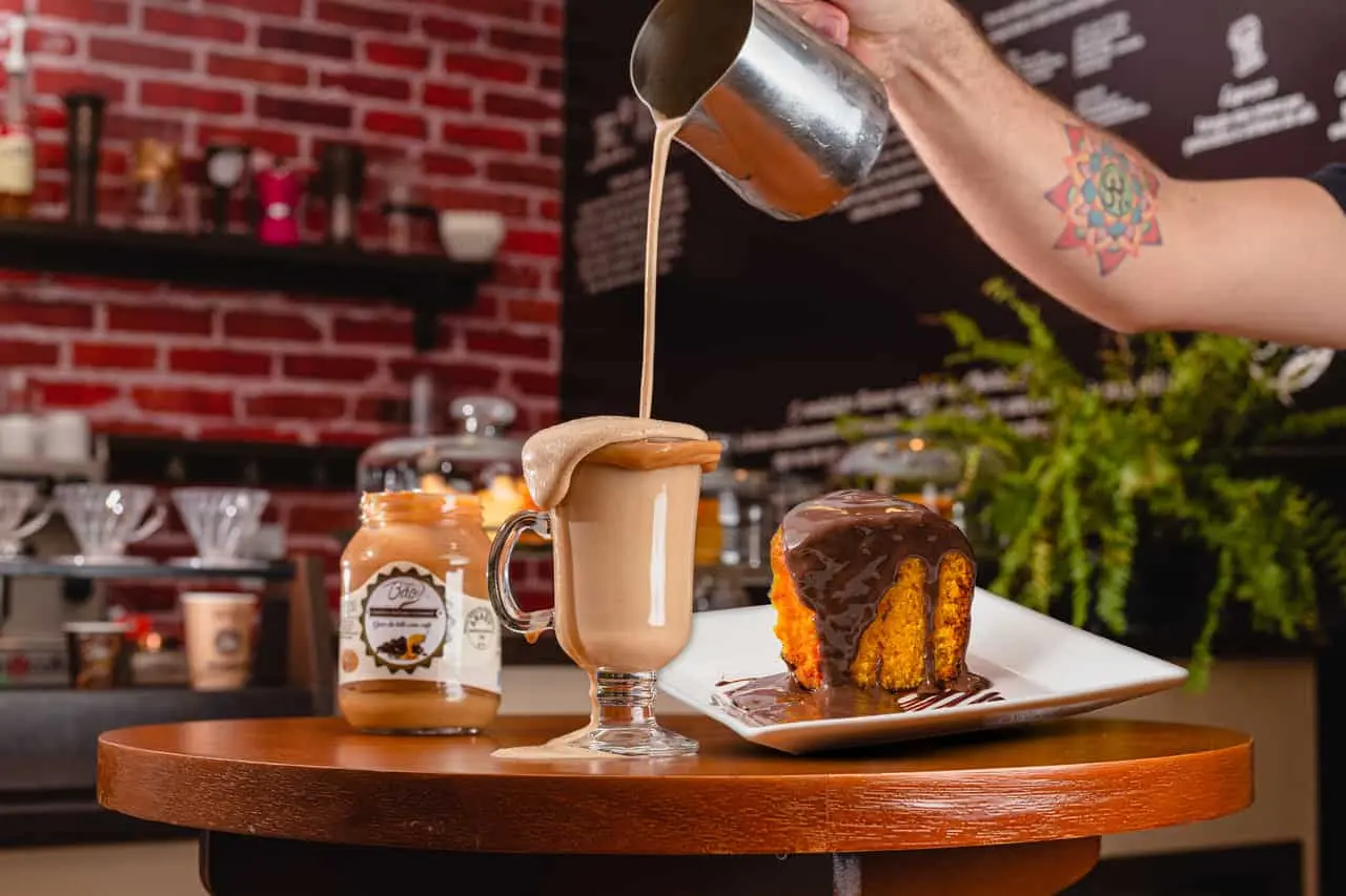 Imagem de chocolatíssimo sendo servido e um pedaço de bolo de cenoura com cobertura de chocolate